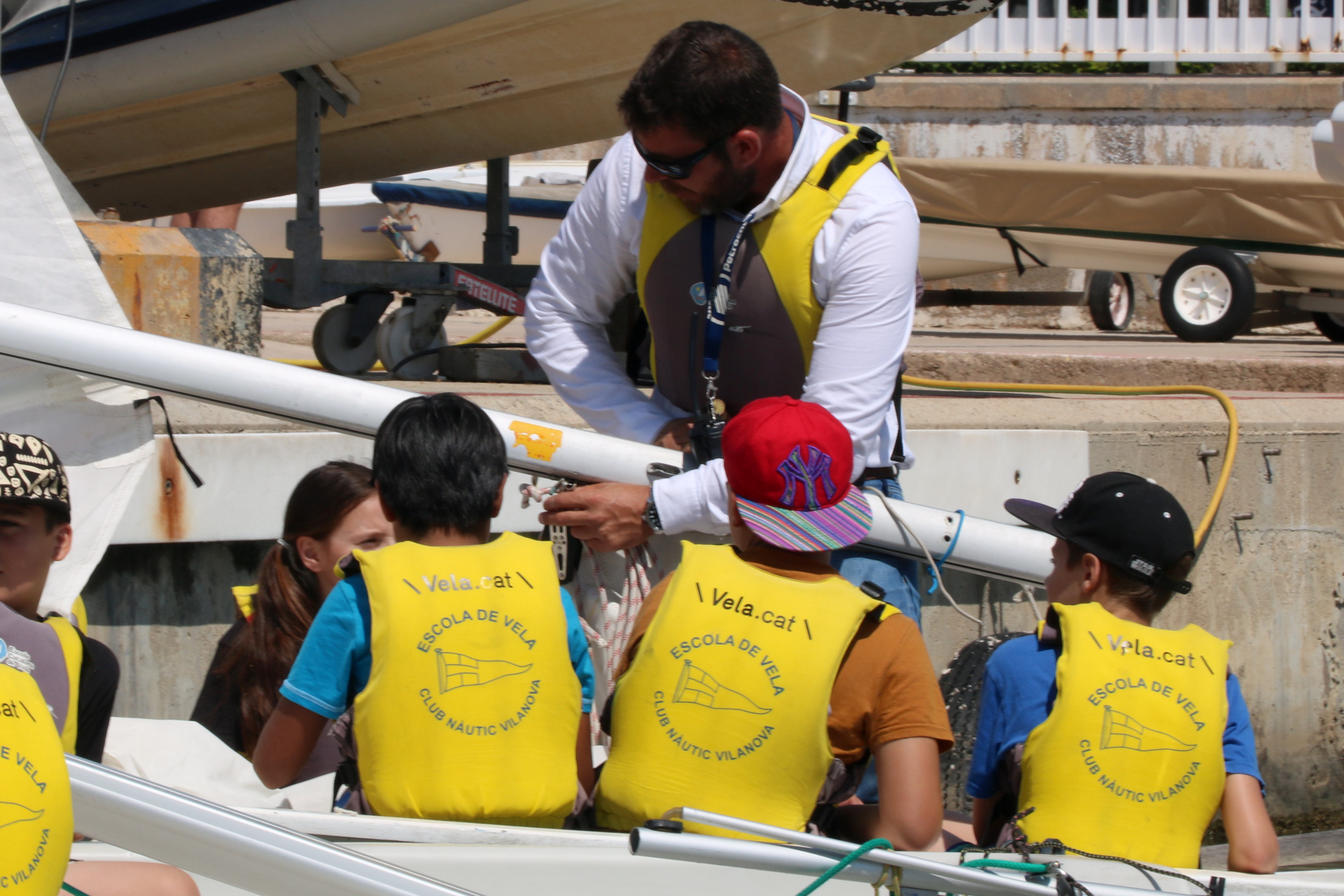 Un grup d'alumnes de l'escola Arjau de Vilanova i la Geltrú escoltant les indicacions d'un monitor de vela | ACN