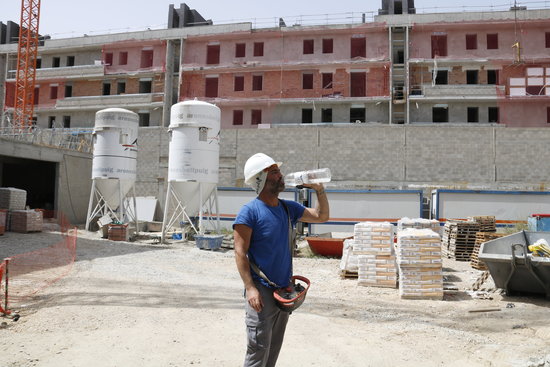 Un operari bebent aigua durant una pausa de la feina a la construcció | ACN